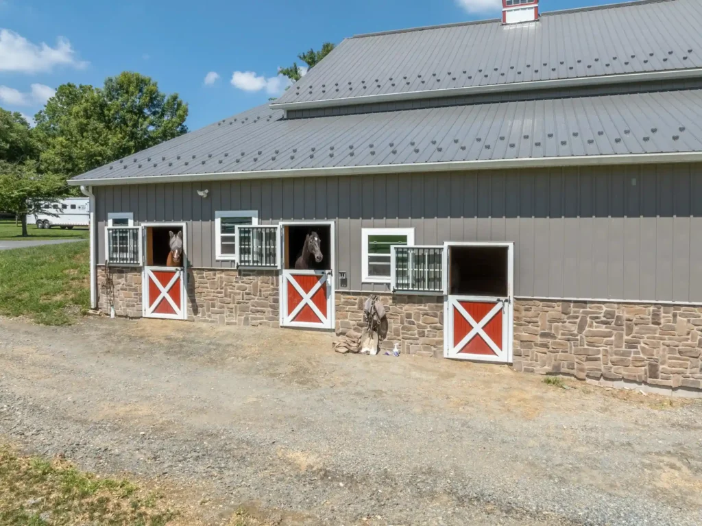 Horses look out of stalls in a custom horse barn built in Lancaster County by Double S Construction.